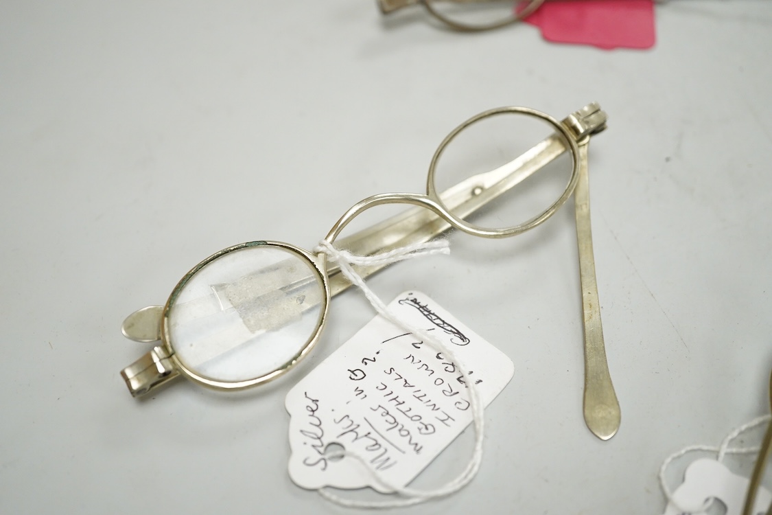 Three pairs of early 19th century base metal slider spectacles, pseudo hallmarks, one also stamped Pebbles, and two pairs of similar temple spectacles, the pair with turn pin sides also stamped pebbles, the pair with obl